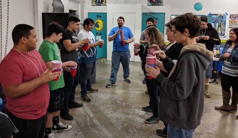 People lined up holding plastic red cups to play a contest