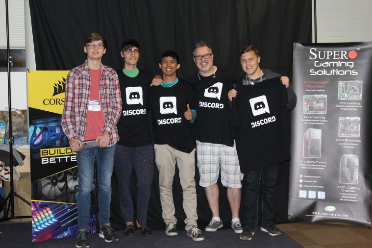 A group of tournament winner holding up Discord t-shirts